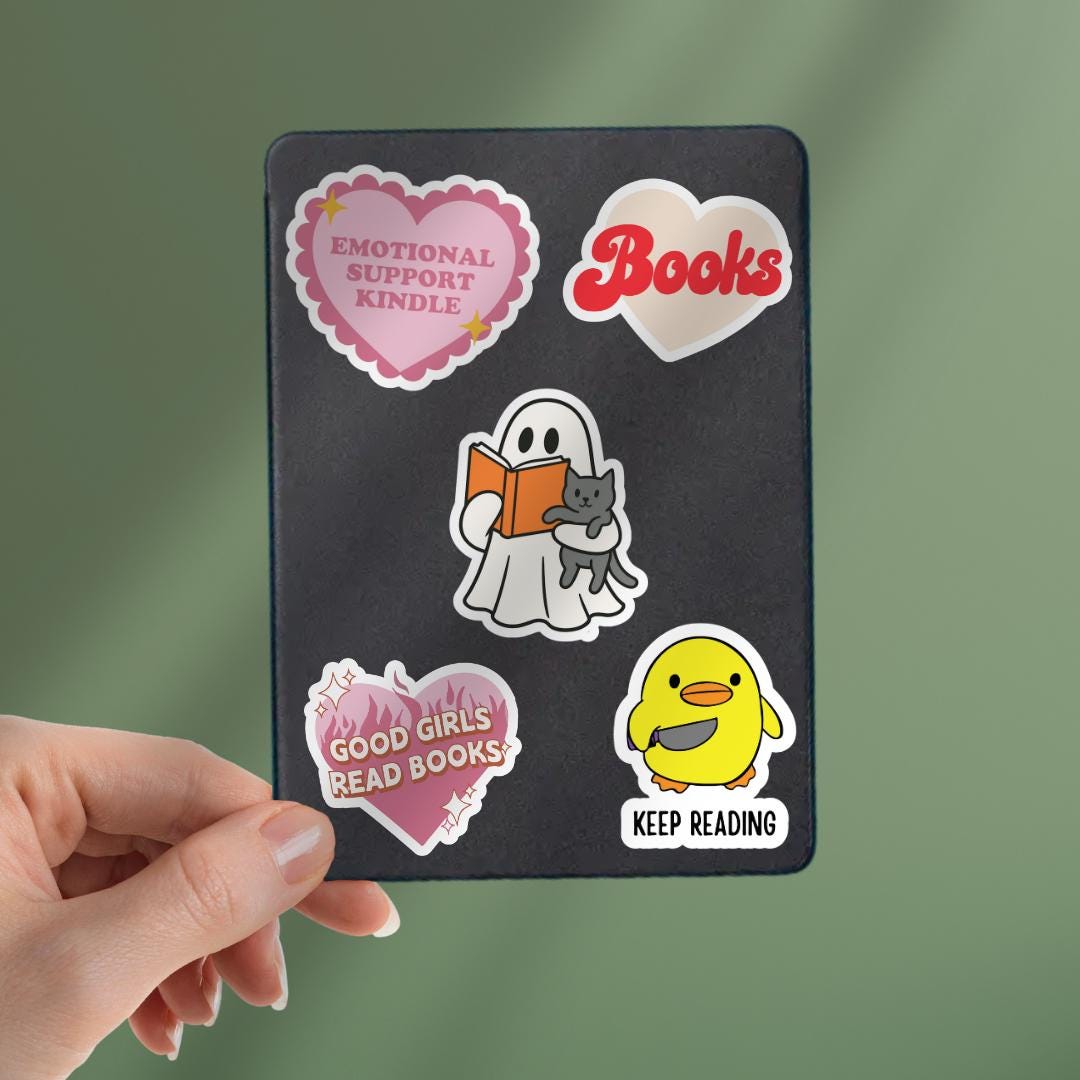 Bookish Ghost Holding Cat Kindle Sticker: Halloween Sticker sticker by Magic & Meaning